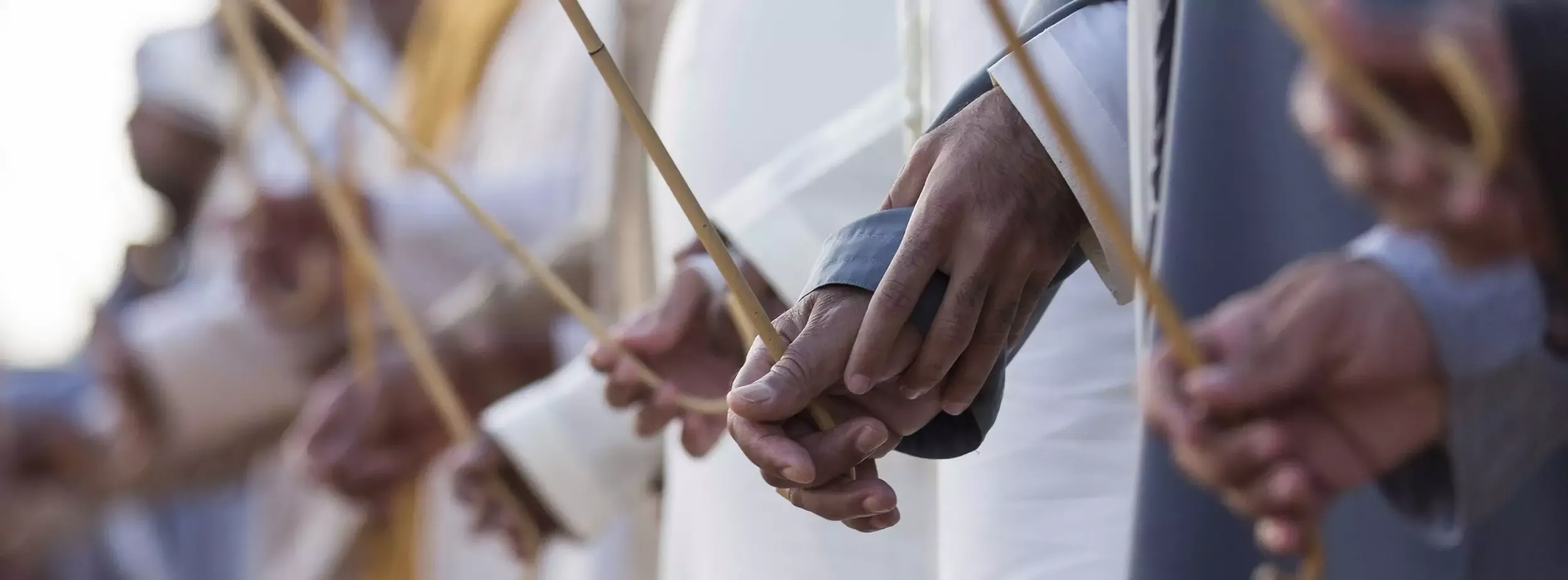 Men holding bamboo sticks, commonly used during the Al Alaya dance.