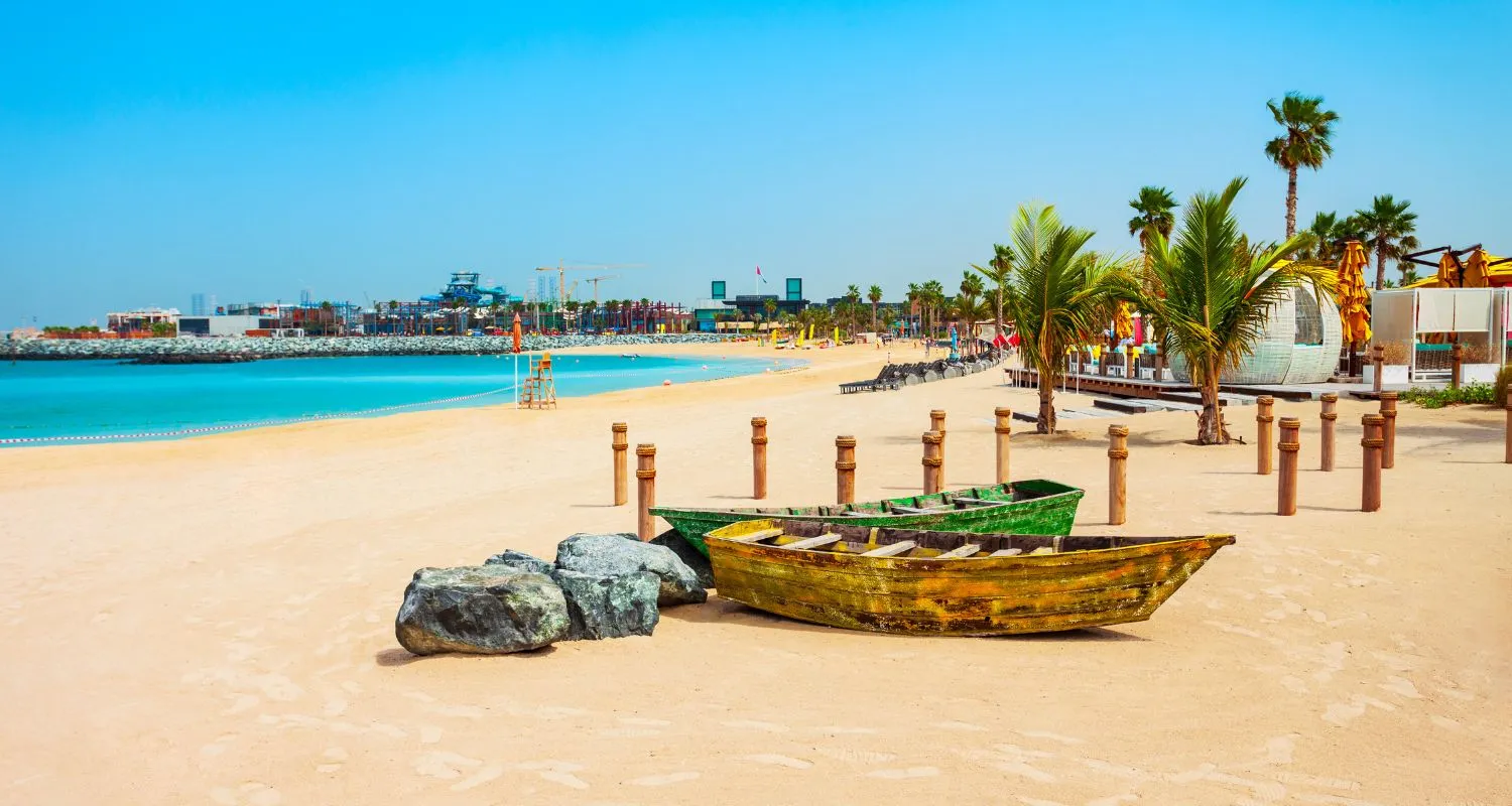Sunny beach with boats and palms.